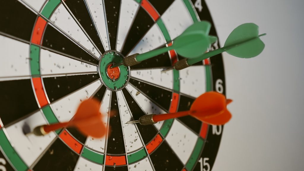 Photo by afif-kusuma-RjqCk9MqhNg-unsplash
Depicts a dartboard with red darts on it