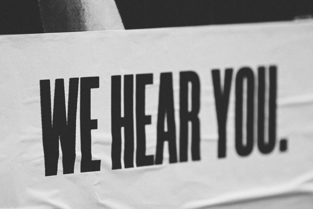 Photo by Jon Tyson on Unsplash
Black and white image showing the text in capital letters: "WE HEAR YOU".